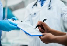 Close-up of woman signing medical agreement at doctor's office.