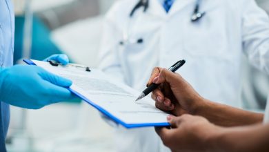 Close-up of woman signing medical agreement at doctor's office.