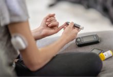 A young teen girl sits on the sofa in the comfort of her own home as she tests her blood sugar levels. She is dressed casually and focused on managing her diabetes.