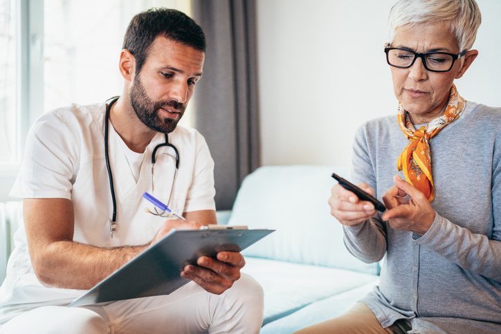 Modern Senior woman doing Diabetes blood test while doctor visits her at home