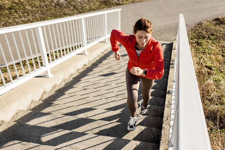 Happy sportswoman jogging at the bridge